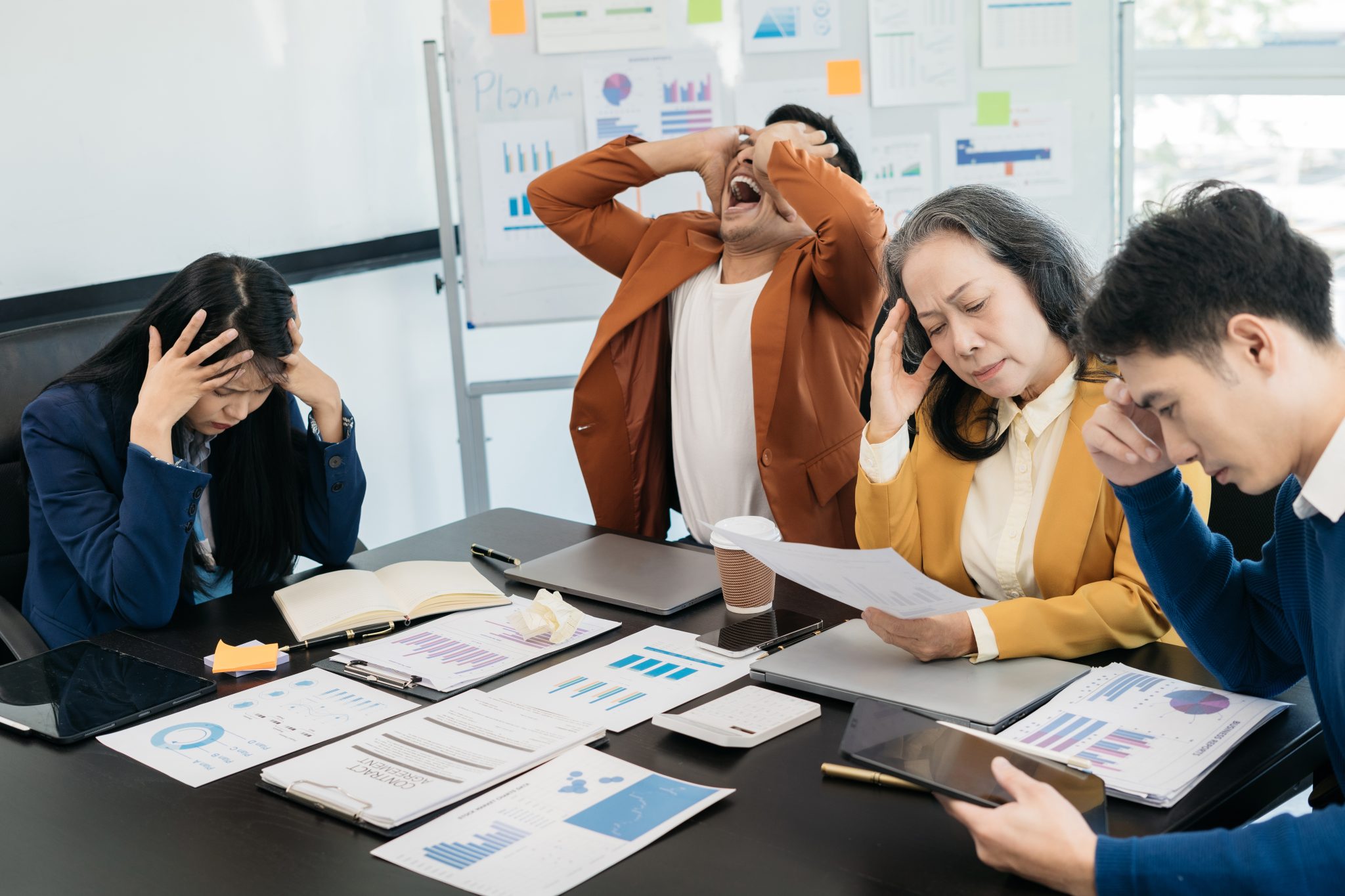 Group of asian business people, teamwork, people and crisis concept - business team sitting sad and solving problems in the office. Failed teamwork concept